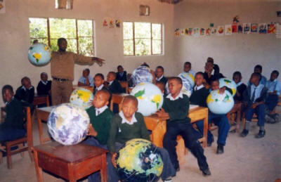 young students holding inflatable globes in a classroom